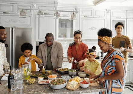 A happy family gathers in the kitchen to prepare a delicious meal together, fostering togetherness and joy.