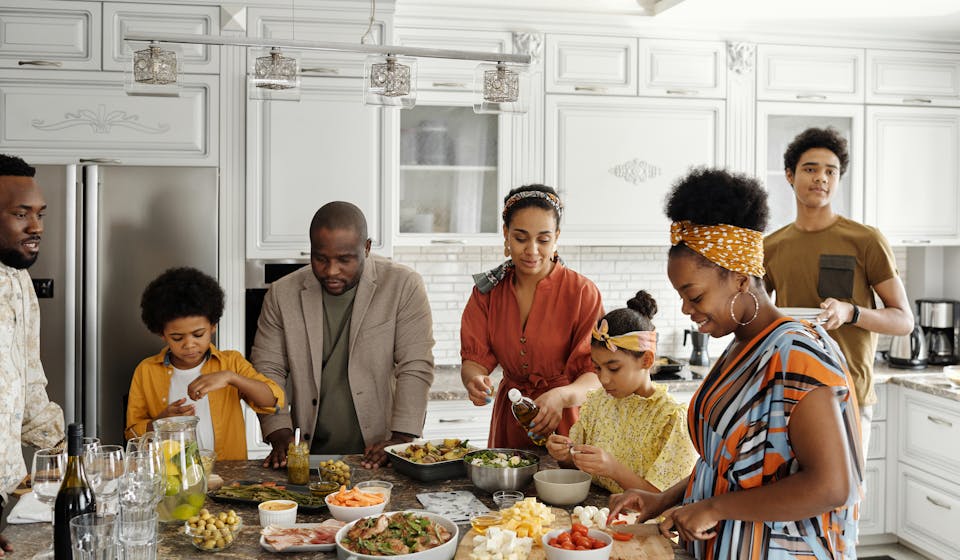 A happy family gathers in the kitchen to prepare a delicious meal together, fostering togetherness and joy.