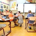Children engaged in learning with a teacher in a bright classroom setting.