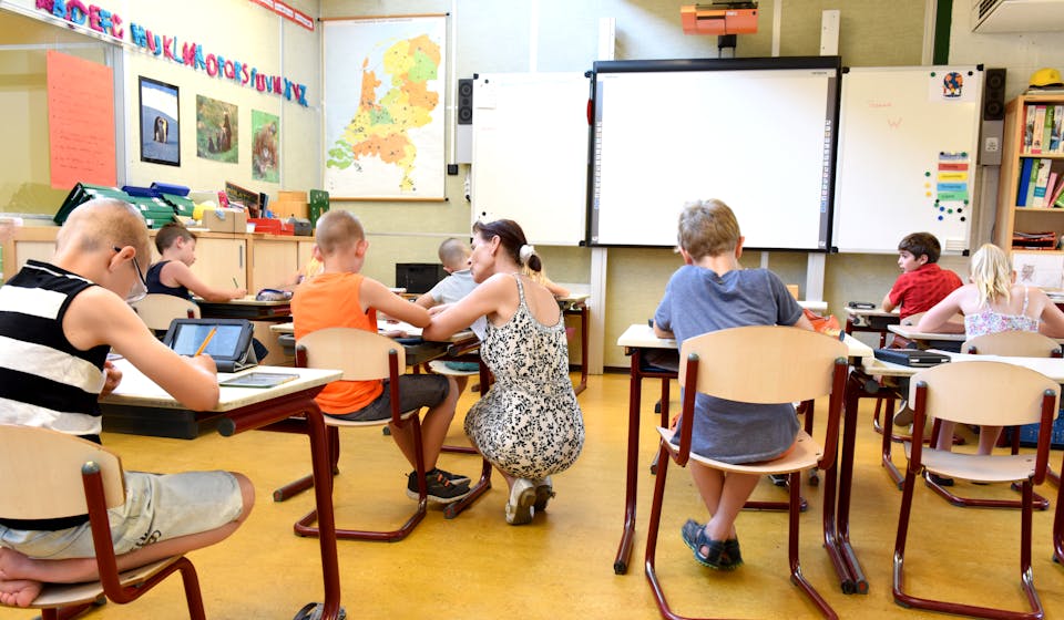 Children engaged in learning with a teacher in a bright classroom setting.